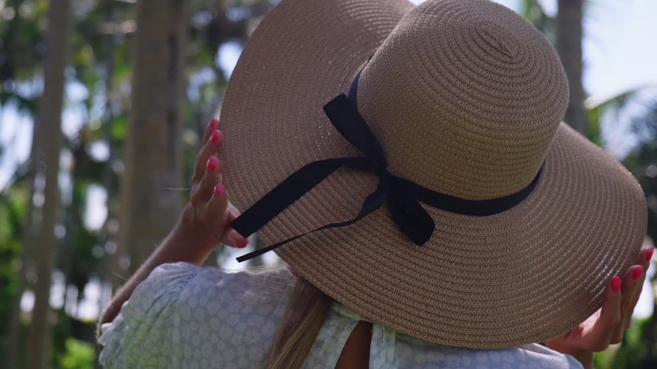 mujer con un sombrero de paja, mirando las palmeras