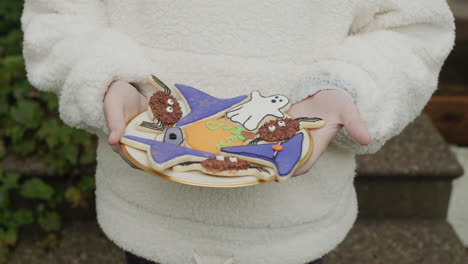 girl holding a plate of handmade halloween cookies