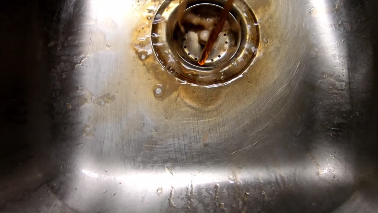 Pouring out two liters of nearly flat soda into a sink