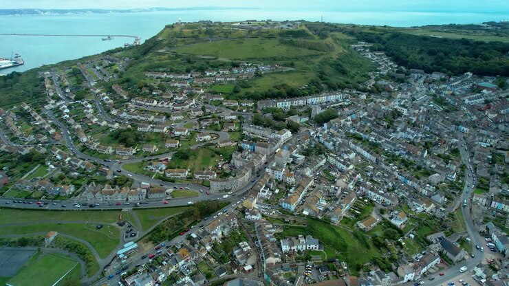 Aerial pull out reveal over Underhill and Fortuneswell Village on the Isle of Portland with Fleet Lagoon in the background and Chesil Beach in the foreground