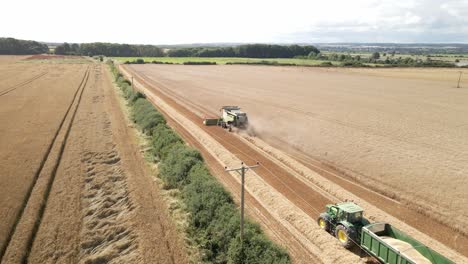 aerial footage of a combine harvester and tractor harvesting a wheat crop