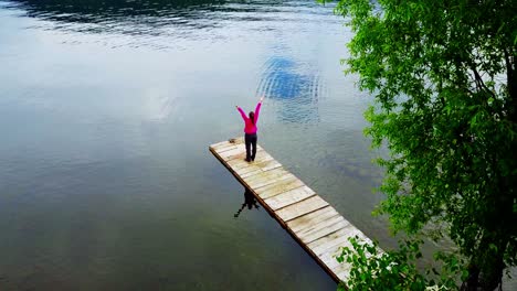 woman enjoying the peaceful lake view from a wooden pier