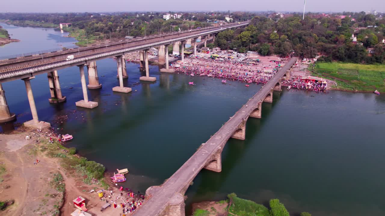 Narmada Ghat with gathering or mela and Tilwara Narmada River Bridge at jotpur, jabalpur, madhya pradesh, india. day time, semi orbit, drone shot, 4k.