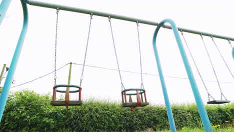 empty swings in a public children's playground with no people on a cloudy day during the coronavirus pandemic