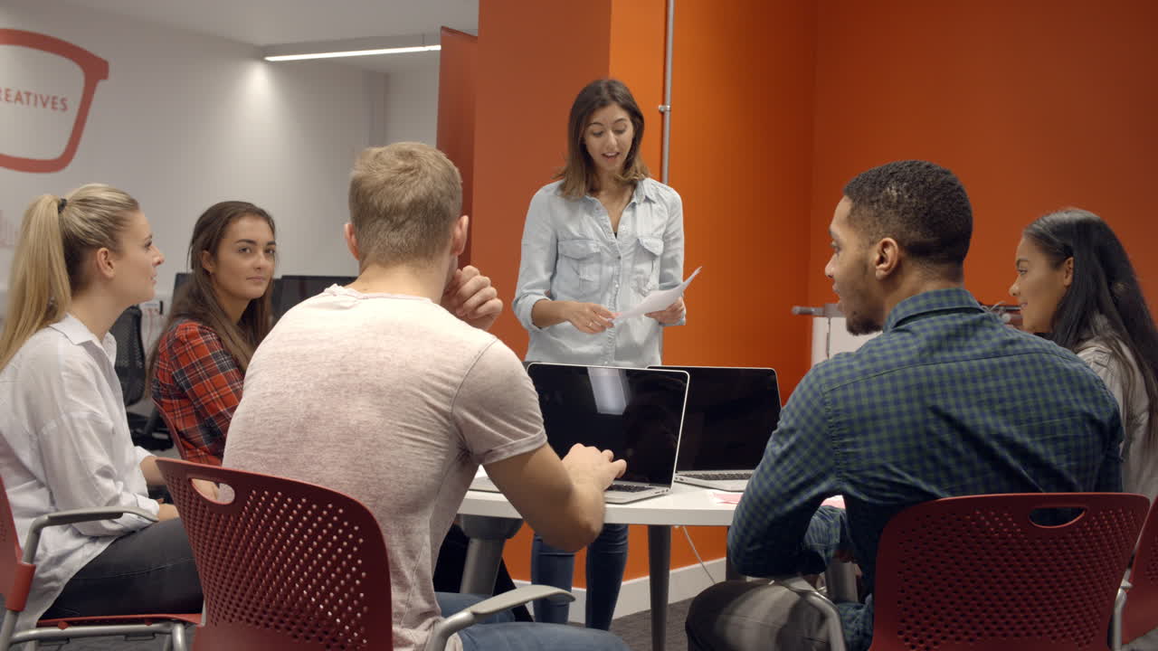 profesor hablando con estudiantes universitarios en la clase de estudios de medios