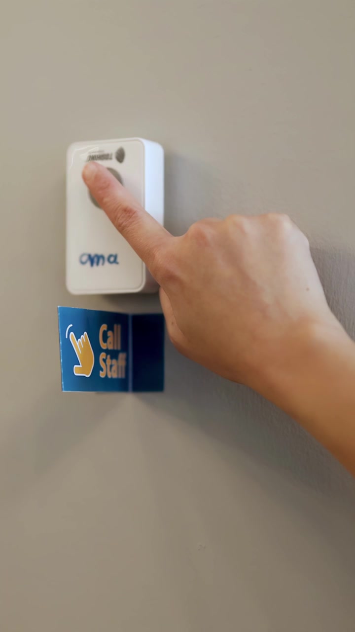 Hand presses wall-mounted call staff button in restaurant, neutral lighting, steady close-up perspective