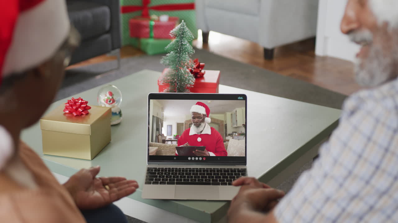 feliz pareja de ancianos afroamericanos en videollamada con santa claus en navidad