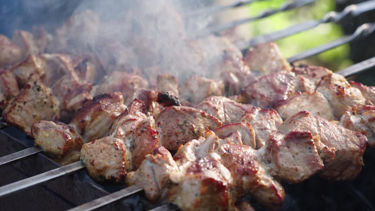 asar carne de cerdo jugosa y marinada con especias y hierbas en carbón quemado en una parrilla de barbacoa, humo en cámara lenta