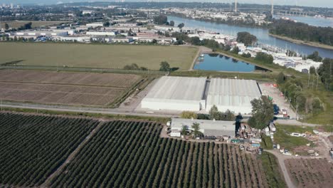 aerial flyover medicianl grade cannabis marijuana plant processing greenhouse on a sunnay day property thats bob wired and gated with governement regulated security staff in richmond bc canada 1-2