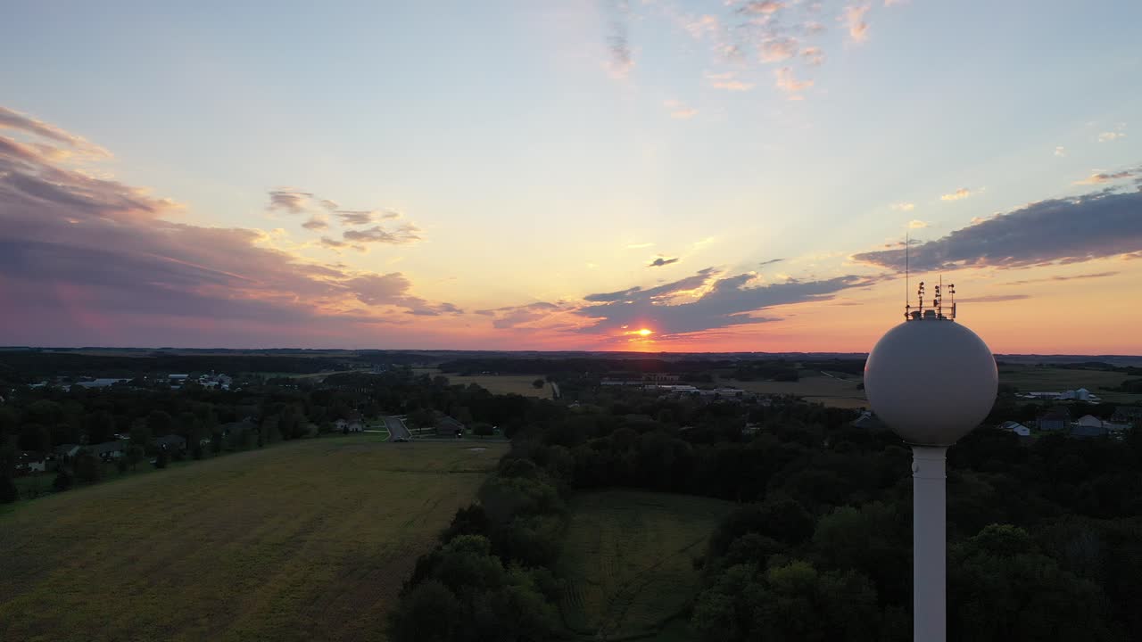 물탑 을 가진 시골 마을 위 의 해가 지는 것