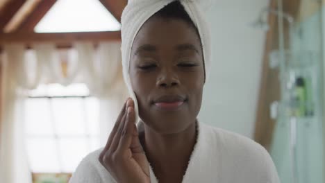 portrait of african american attractive woman removing make up in bathroom