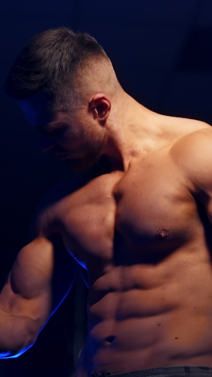 Man posing in gym. Handsome mature man standing strong in the gym and flexing muscles. Vertical video