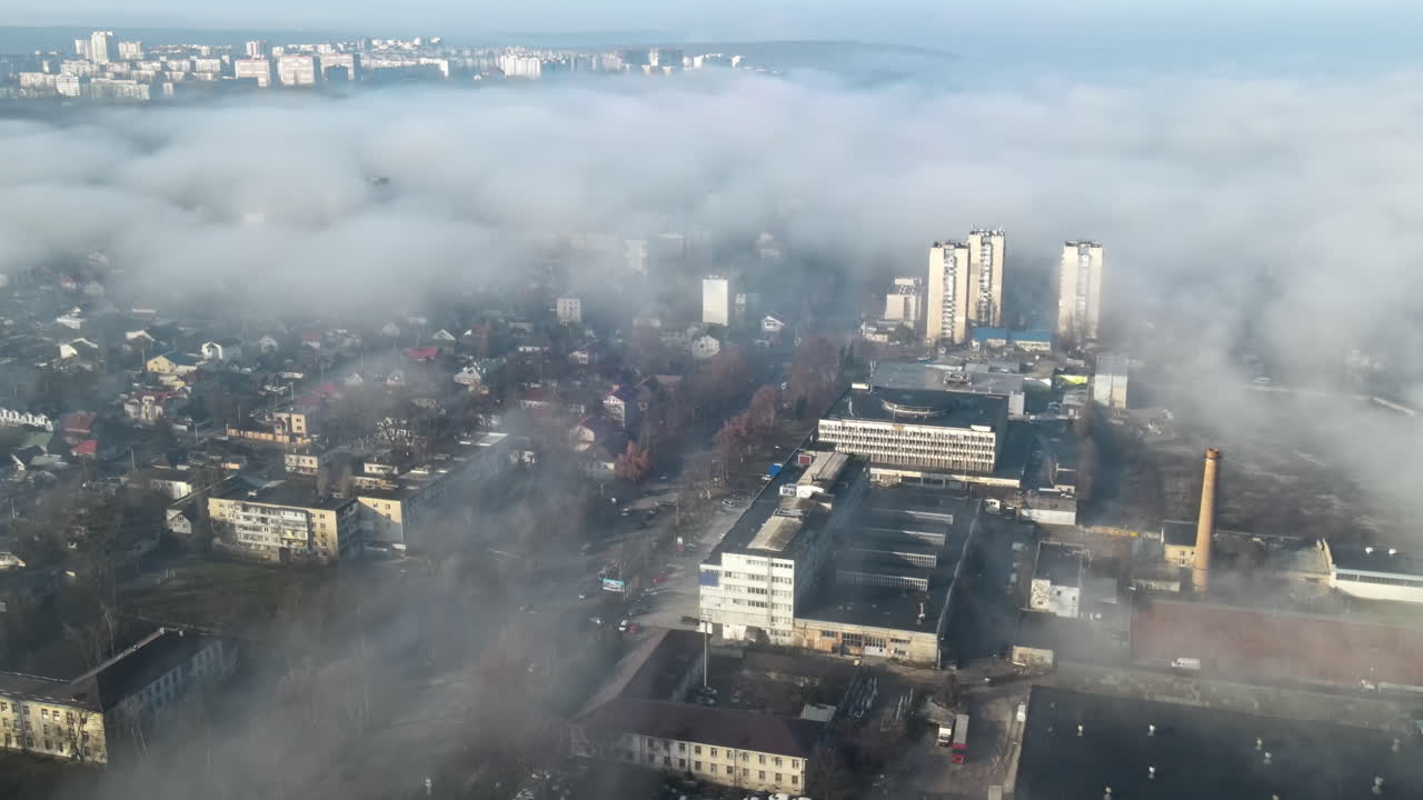 Aerial drone view of Chisinau through the clouds. Panorama view of multiple buildings, roads with moving cars and bare trees. Moldova