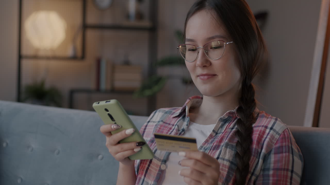 Woman using smartphone and credit card for online shopping at home