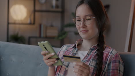 woman using smartphone and credit card for online shopping at home