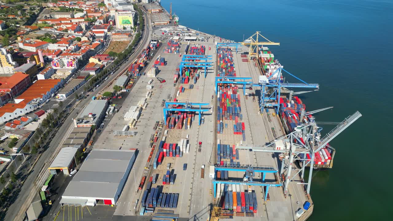 Aerial view over the container terminal in Santa Apolonia with two ships loaded with containers moored at the pierand lisbon cityscape at background,Portugal