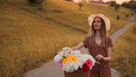 Mädchen-Im-Mittleren-Plan-Im-Kleid-Geht-Mit-Fahrrad-Und-Blumen-Auf-Dem-Feld