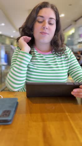 woman ordering food on tablet in coffee shop