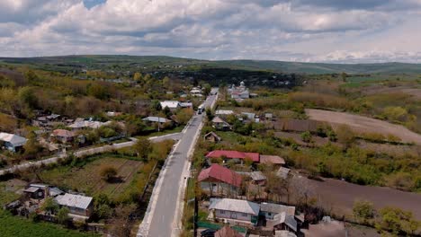 aerial view over an old village road and houses, agricultural fields, church, partly cloudy, sunny day