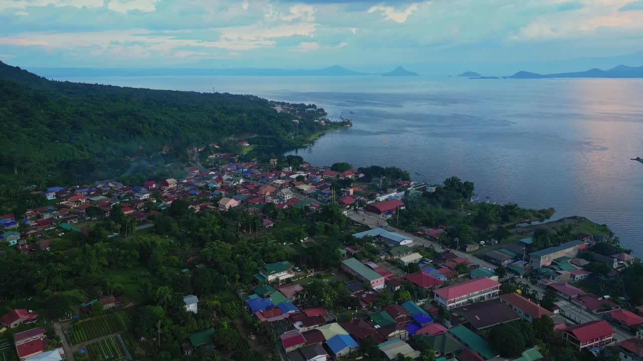 A slow rising aerial of Talisay town nestled along the forested edge of Taal Lake in Batangas, Philippines