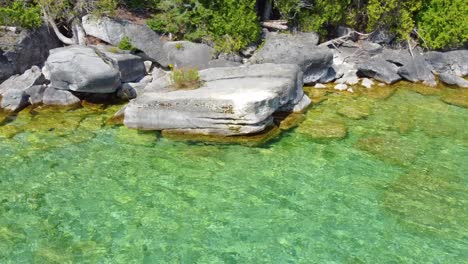 clear waters of lake huron washing the bruce peninsula shoreline, aerial dolly left to top down shot