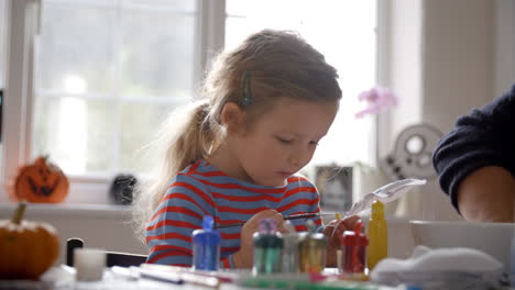 padre e hija pintando máscaras en casa juntos