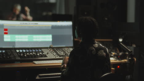 music producer working on vocal track with female singer in recording studio