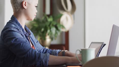 mujer biracial ocupada trabajando en casa con una tableta en cámara lenta