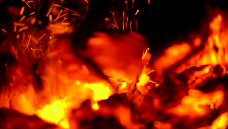 iron poker stirs hot coals of burning fire close up