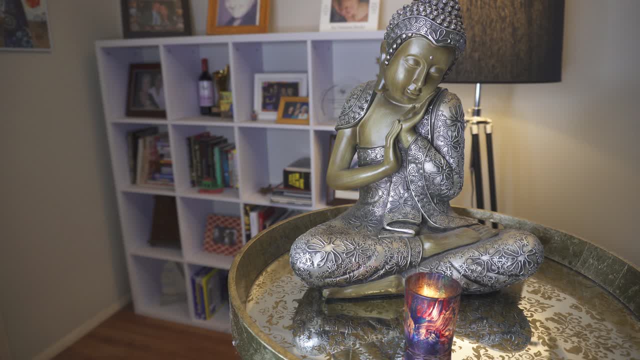 figura de buda frente a una vela brillante en la sala de estar, estudio, calma