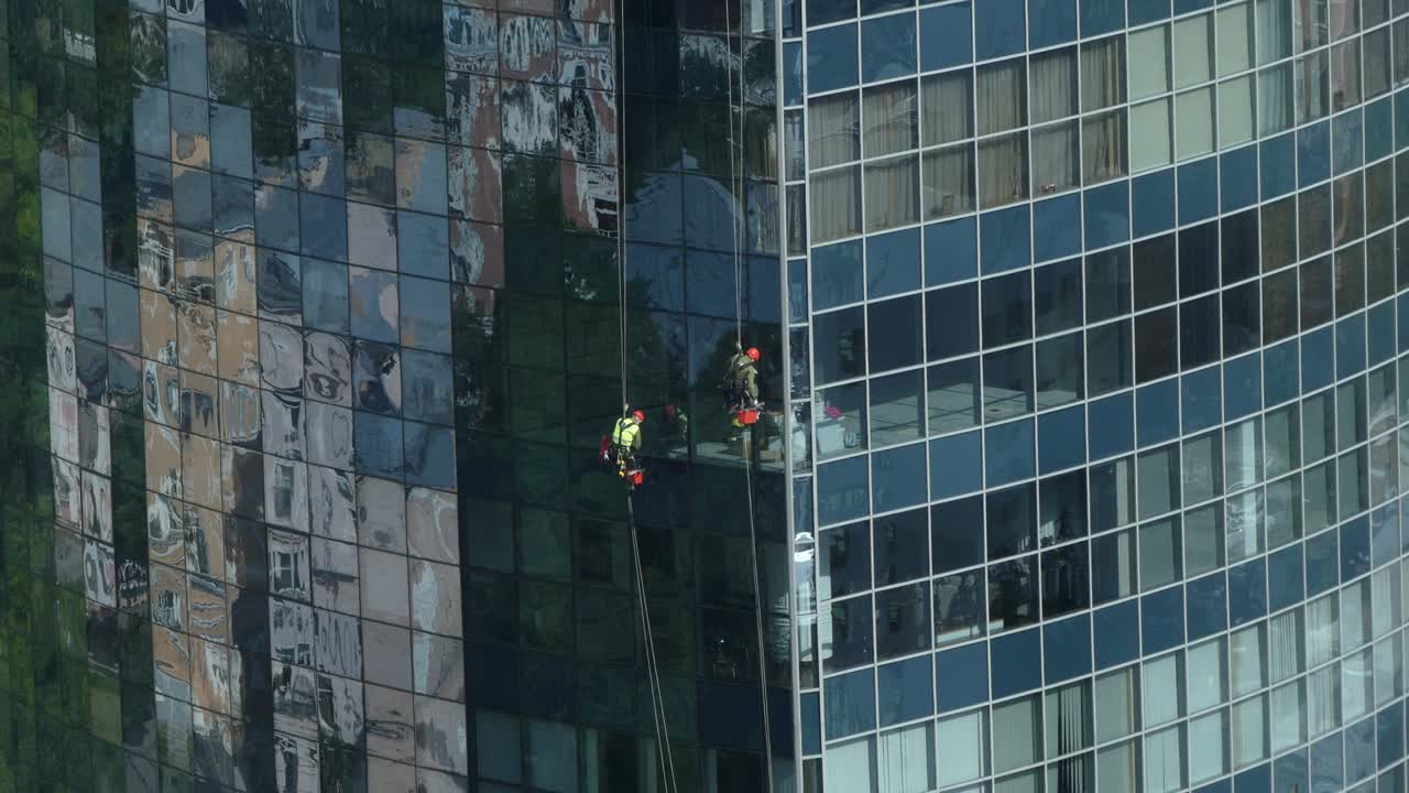 trabaja en alta altitud. un trabajador lava las ventanas de un rascacielos. el escalador lava ventanas en altura. un esturión lava ventanas de un rascacielo.