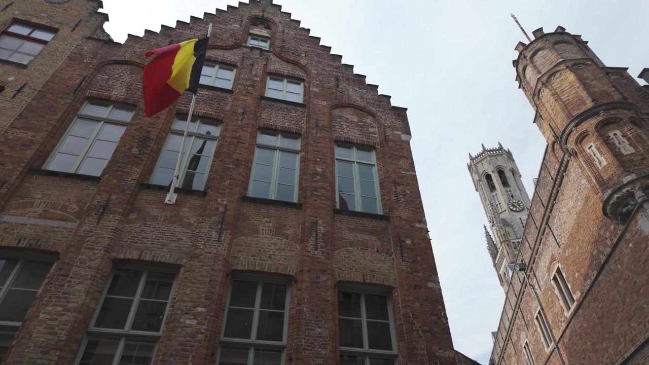 Brugge Pazar Meydanı, Belfry (Çan Kulesi) ve gri gökyüzü altında tarihi mimari.