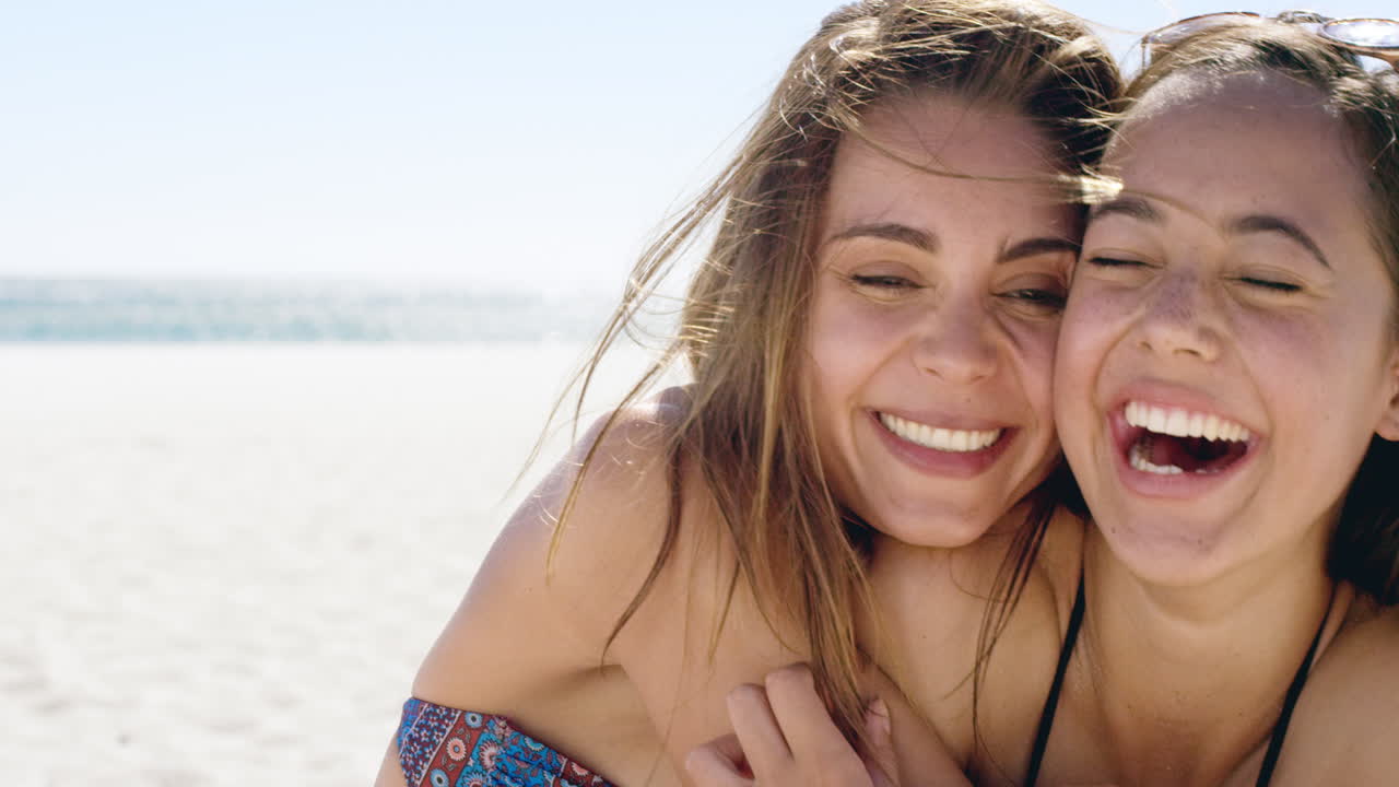 uma jovem bonita a beijar uma amiga adolescente na bochecha, abraçando-se nas férias.