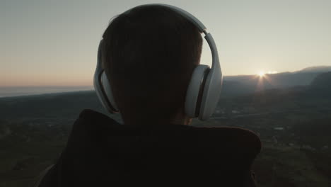 man listening music at sunset