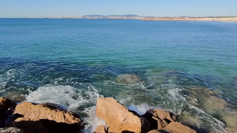 Walking-along-stony-and-rocky-beach-with-crystal-clear-turquoise-sea-water-lighting-during-sunny-day