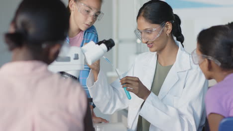 in school, teacher using microscope and explaining science experiment to students