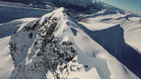 Rocky-peaks-covered-in-snow-in-Norway,-aerial-FPV-extreme-view