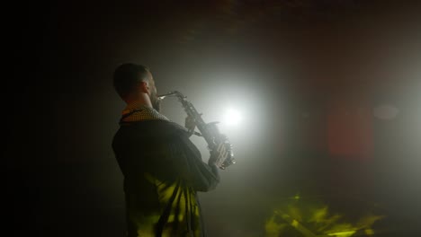 Live-performance-of-saxophonist-man-with-saxophone,-dancing-on-concert-musician-stage-with-lights