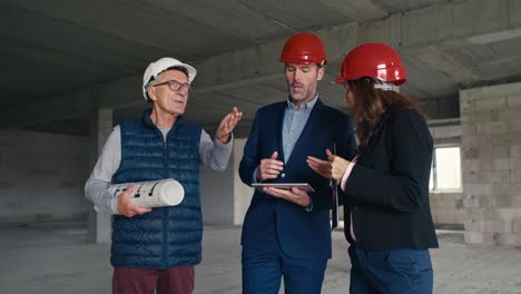 grupo de ingenieros caucásicos e inversores caminando y discutiendo en el sitio de construcción.
