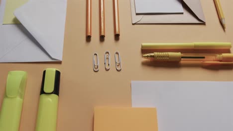 close up of pens, pencils and stationery arranged on beige background, in slow motion