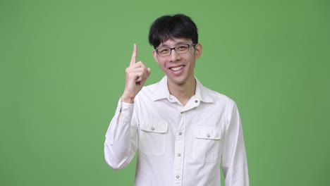 young happy asian businessman smiling while pointing up