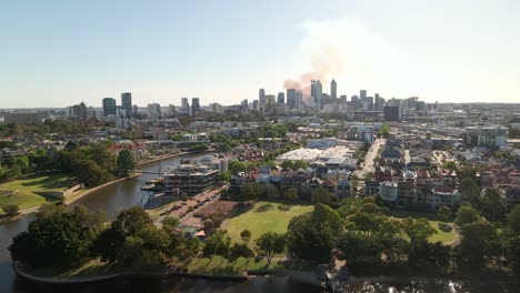 tracking aerial shot of perth cbd with smoke in the background from a fire