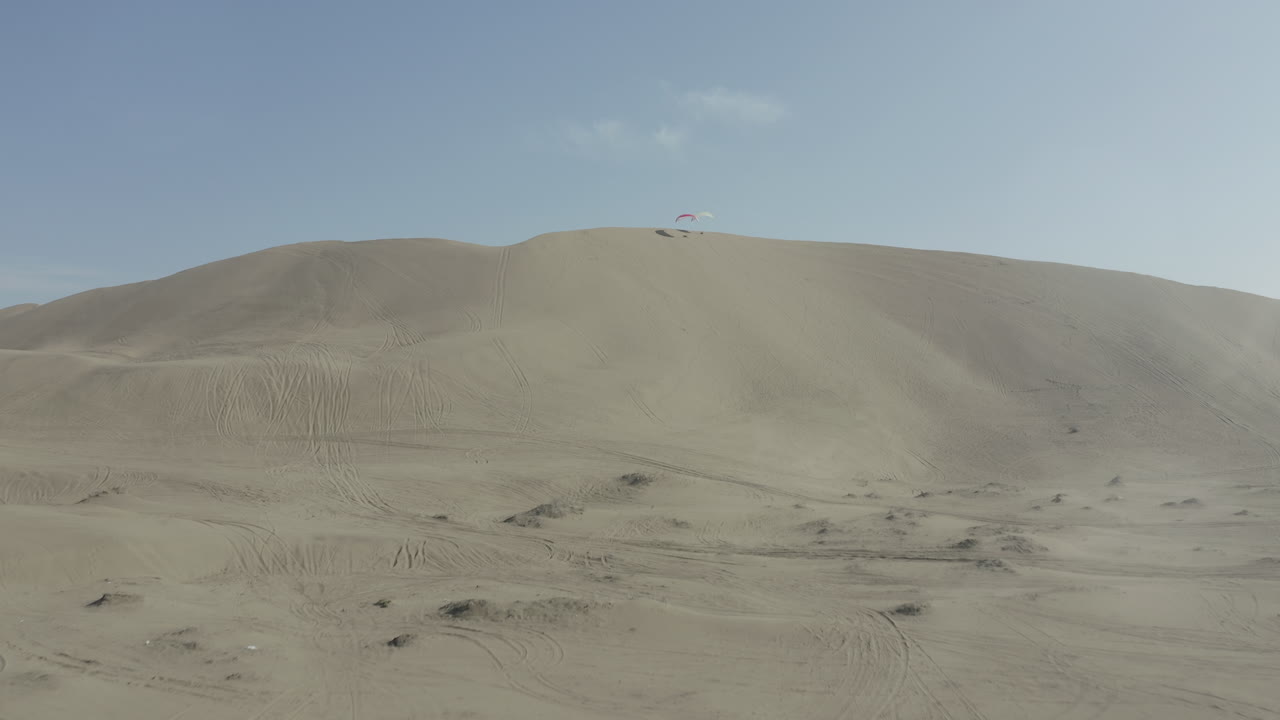 Paragliders resting, showcasing an aerial view of vast sand dunes