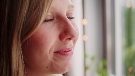 blonde-woman-with-blue-eyes-looking-out-of-the-window,-closeup