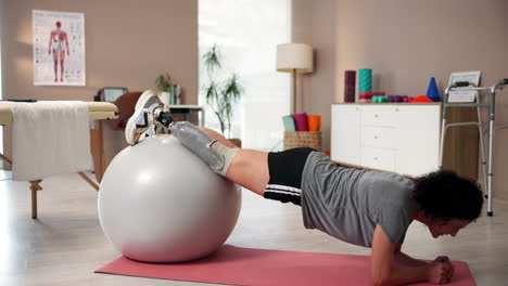 woman with a prosthetic leg exercising with an exercise ball in a physical therapy setting