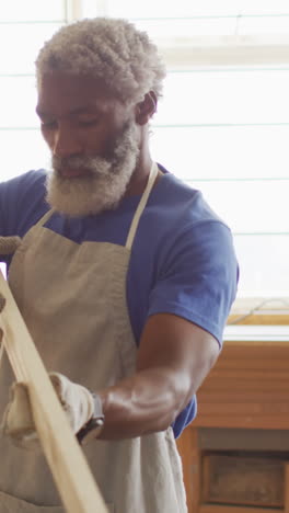 african american craftsman examines a piece of wood in his workshop