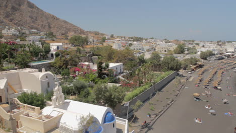 Toma-Panorámica-Lenta-Desde-Un-ángulo-Alto-De-La-Playa-Negra-De-Kamari-En-La-Isla-De-Santorini