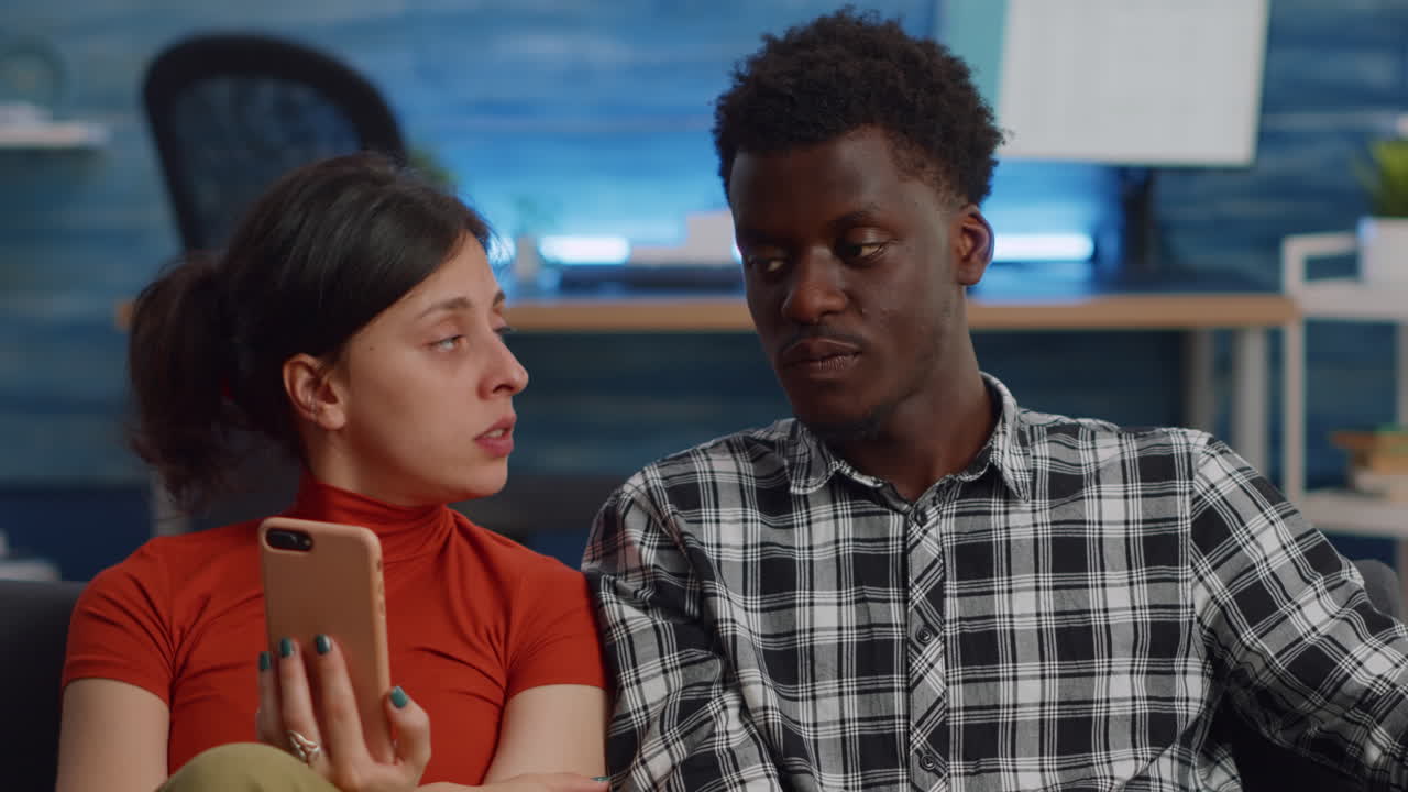Married interracial couple using smartphone at home