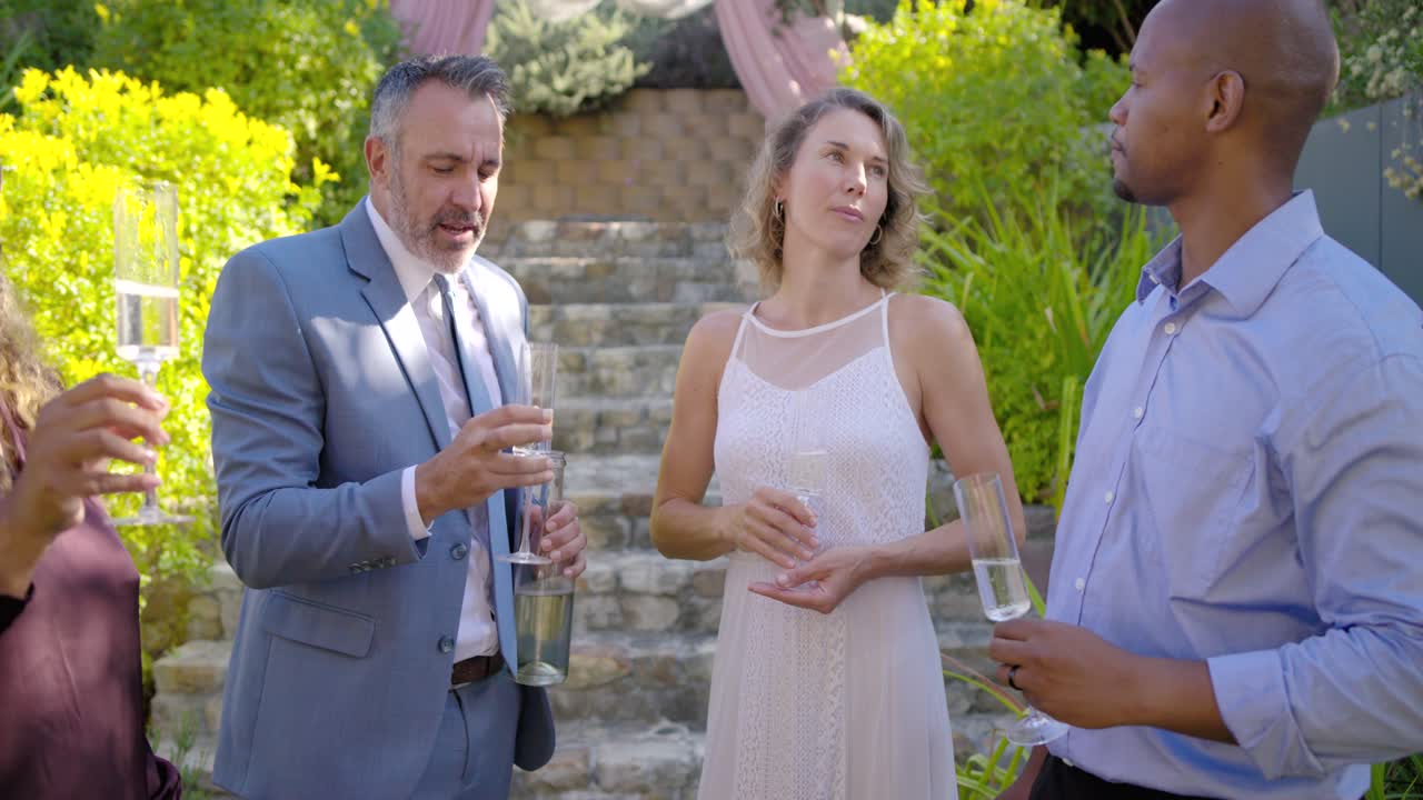 Anfitrião erguendo taça para brinde, trio central brindando com taças, entregando garrafa, celebrando casamento
