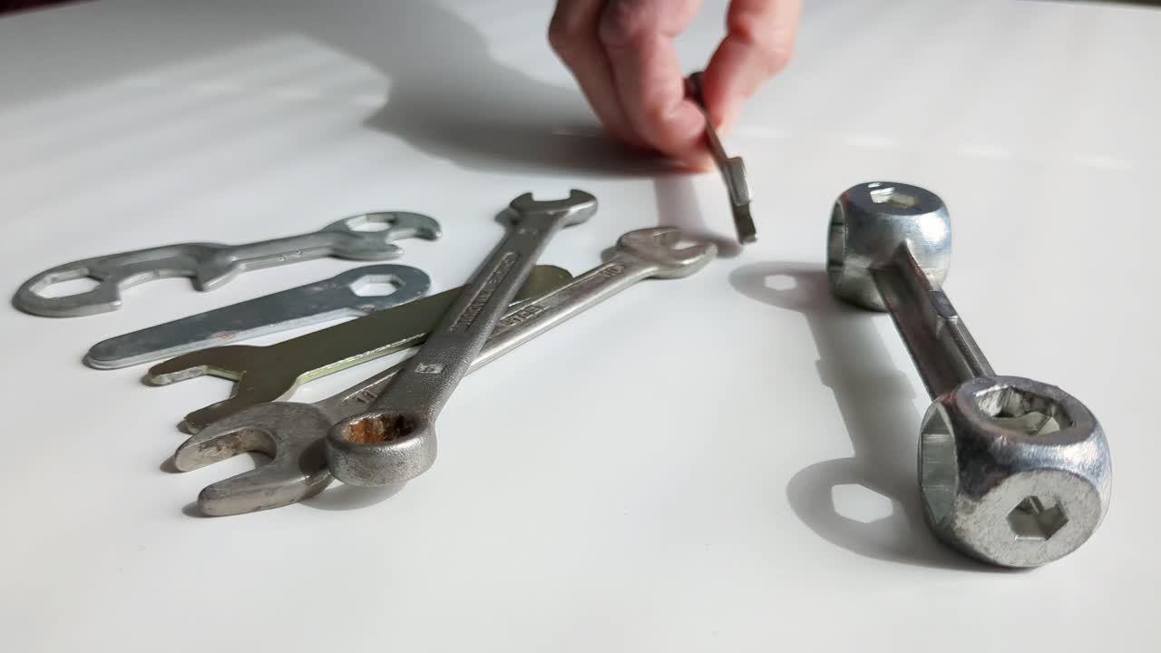 Woman choosing tool from multiple spanner tools on worktop, close up